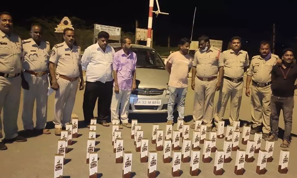 SEB Circle Inspector P Srinivasulu and his staff with the seized liquor bottles at Panchalingala border check-post on Tuesday.