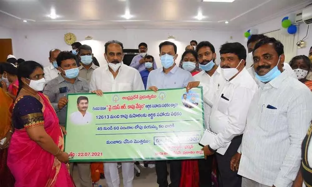 Minister Balineni Srinivasa Reddy and Collector Pravin Kumar holding a symbolic replica of YSR Kapu Nestham financial assistance in Ongole on Thursday