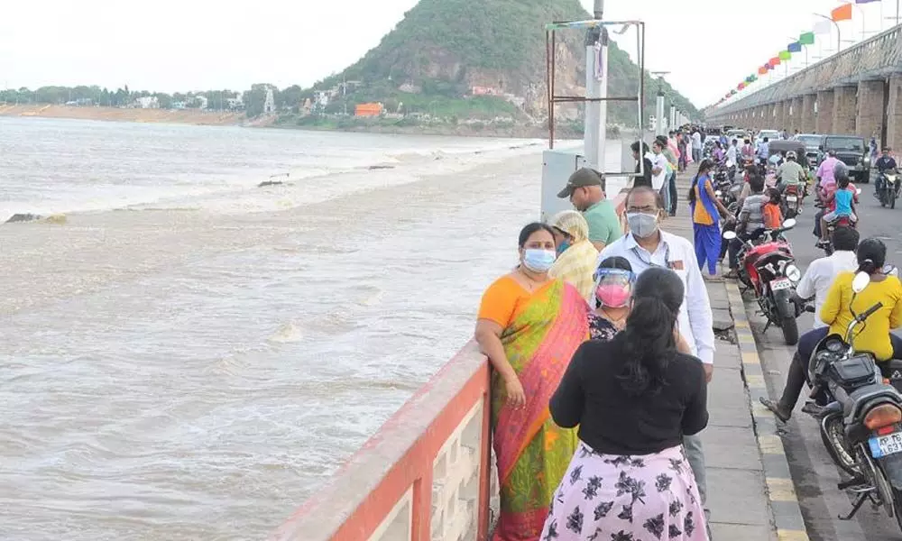 Visitors watching water discharge into sea at Prakasam barrage in Vijayawada on Sunday
