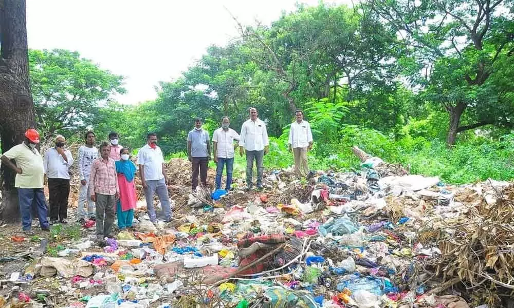 CPM leaders observing the garbage piled up in the park in Khammam on Monday