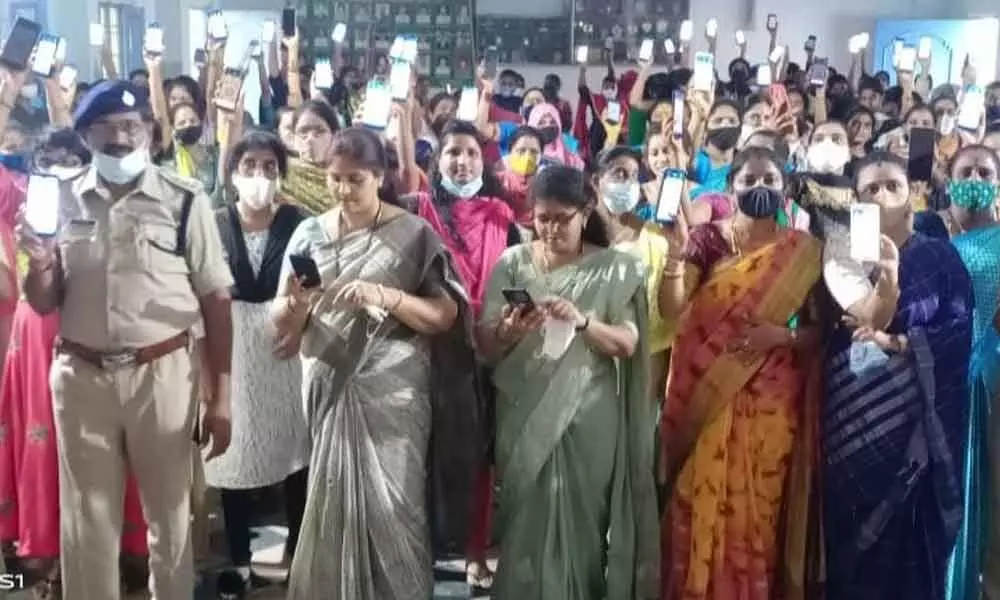 Women downloading Disha app on their mobile phones at Ichchapuram in Srikakulam district on Monday