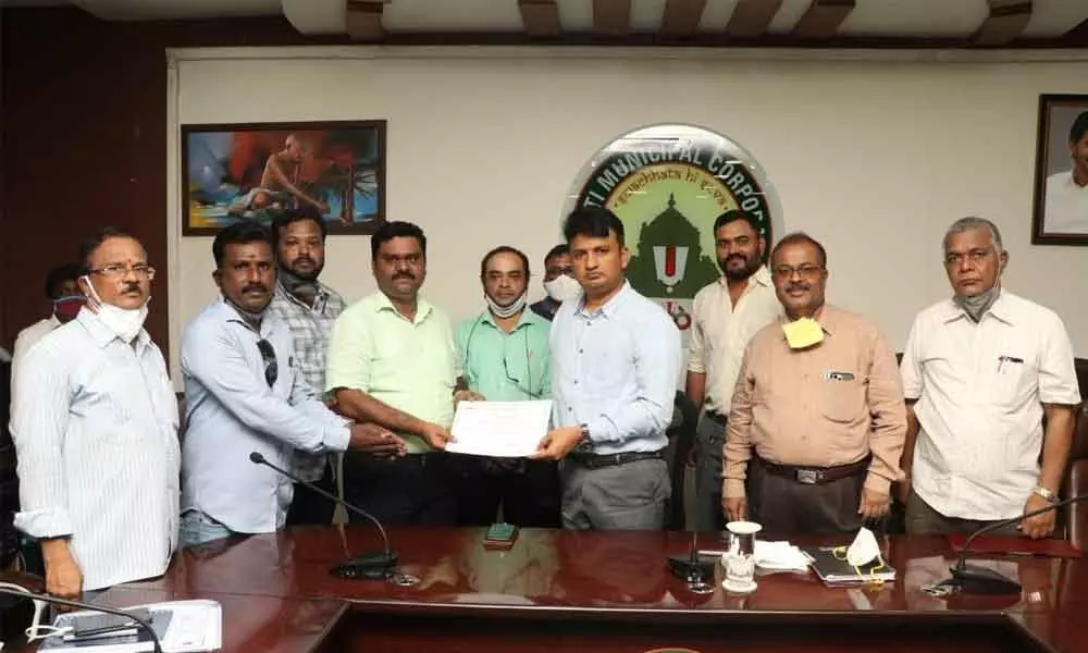 Municipal Commissioner P S Girisha presenting certificate of appreciation to Afcons Infra project manager Ranga Swamy and to his team at the municipal office in Tirupati on Saturday