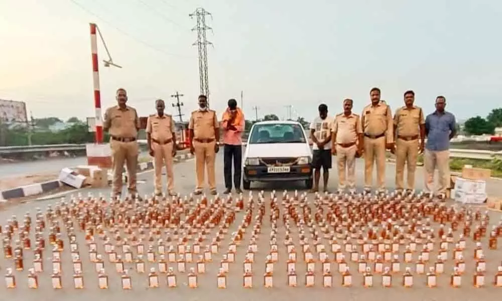 SEB Circle Inspector P Srinivasulu and his staff with seized liquor bottles and the accused at the Panchalingala border check post on Monday.