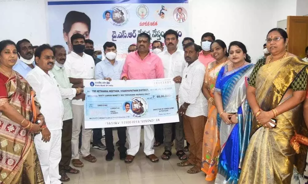 Tourism Minister M Srinivasa Rao handing over a replica of a cheque to the District Collector as a part of the YSR Nethanna Nestham in Visakhapatnam on Tuesday