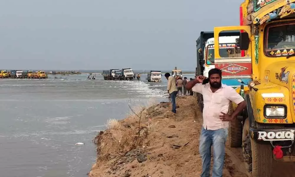 Trucks stuck in Krishna river floodwaters at a sand quarry near Chevitickallu in Krishna district on Saturday
