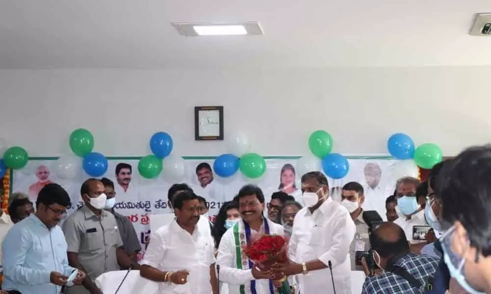 Minister for Municipal Administration and Urban Development Botcha Satyanarayana presenting a bouquet to J Prasanna Kumar who took over as the new chairman of APTIDCO in Vijayawada on Saturday