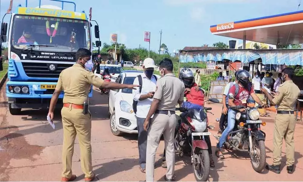 Police personnel check the Covid-19 test report of travellers at Talapady checkpost at Kerala-Karnataka border in Mangaluru. (PTI Photo)