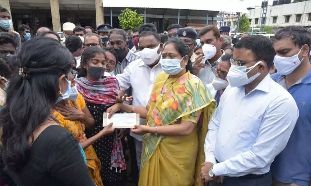 Home Minister Mekathoti Sucharita giving a cheque to the parents of Ramya in Guntur on Monday