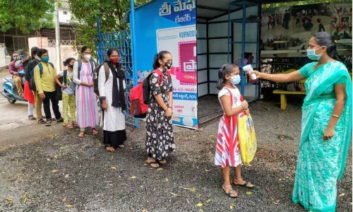 A teacher scanning body temperature of students at a Private School in Ongole on Monday