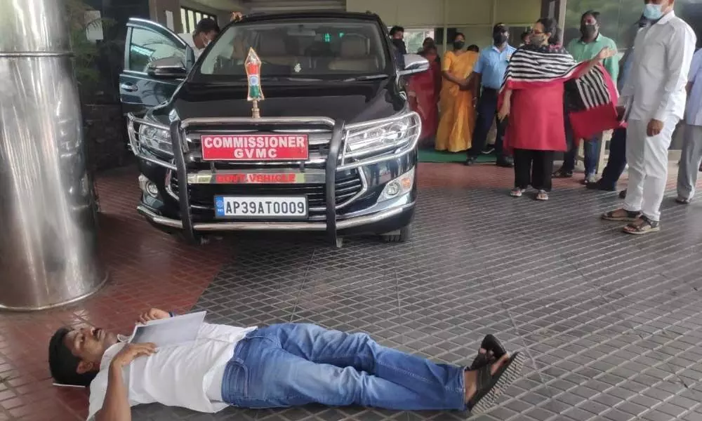 22nd ward Corporator Murthy Yadav staging a protest by lying down in front of the Municipal Commissioners car at GVMC in Visakhapatnam on Tuesday