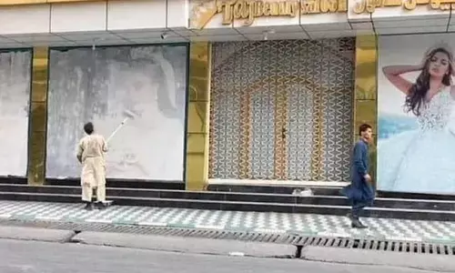 A photo of two men whitewashing such posters in the city has gone viral on Twitter. (Photo | Twitter)