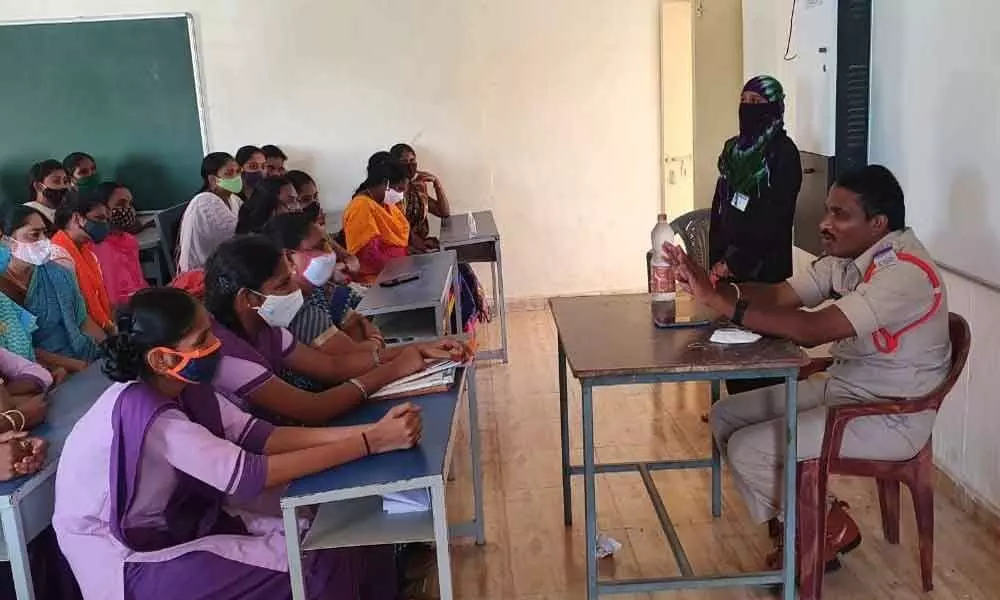Inspector of Police Akula Raghu clarifying the doubts of girl students during an awareness session on Disha app in Tadepalligudem on Thursday