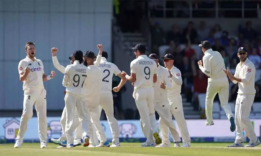 Englands Ollie Robinson (left) and teammates celebrate the dismissal of Indias Cheteshwar Pujara during the fourth day of third Test match at Headingley cricket ground in Leeds, England,  on Saturday