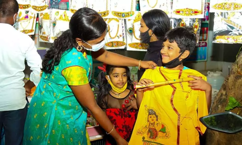 A woman selecting suitable dress at a shop for her son to don Little Krishna role in Tirupati