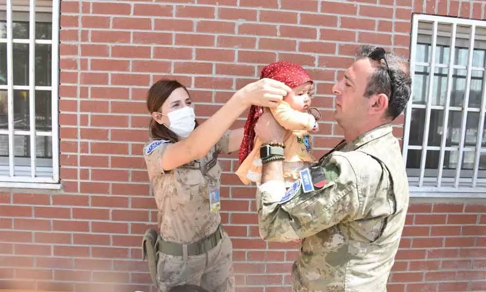 A Turkish soldier extends helping hand to an Afghan baby
