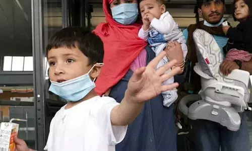 Families evacuated from Kabul, Afghanistan, walk through the terminal before boarding a bus after they arrived at Washington Dulles International Airport. (Photo | AP)