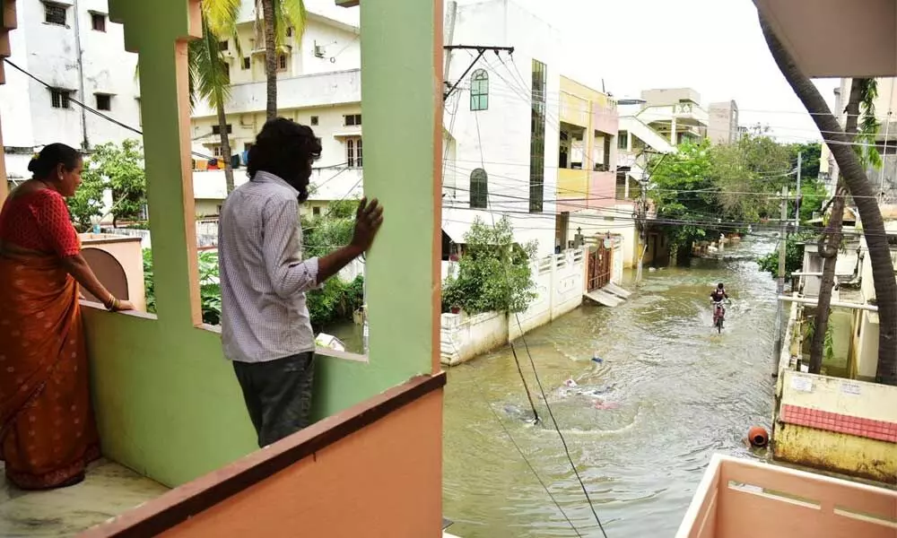 Residents of a locality taking a look at the inundated road following heavy rain in Hyderabad on Friday. 	Photo: Adula Krishna