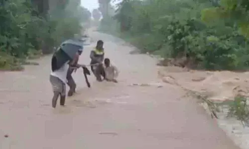 Locals rescuing a youth while he is being washed away in stream at Narsimhula Gudem of Nampally mandal on Friday