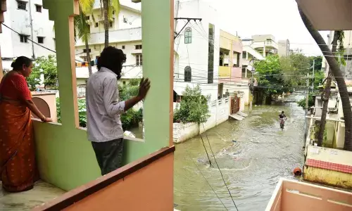 Residents of a locality taking a look at the inundated road following heavy rain in Hyderabad on Friday. 	Photo: Adula Krishna
