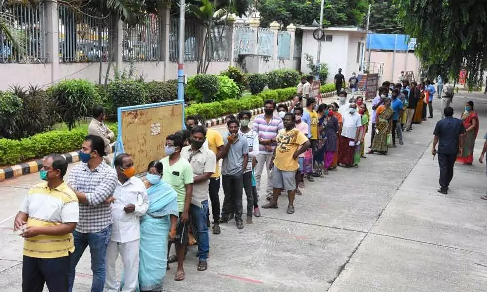 People standing in a long queue waiting for their turn to get ‘Time Slotted Sarva Darshan’ tokens at Tirumala on Wednesday