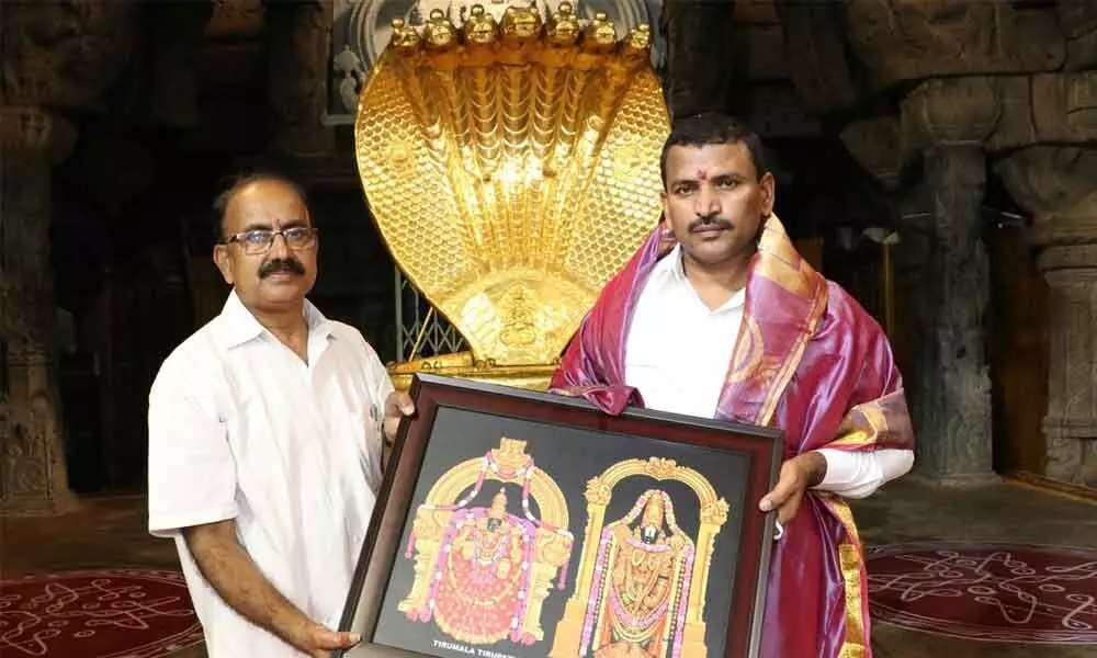 A TTD official presenting the laminated photo of Lord to the newly appointed JEO V Veerabrahmaiah at Ranganayakula Mandapam in Tirumala on Saturday