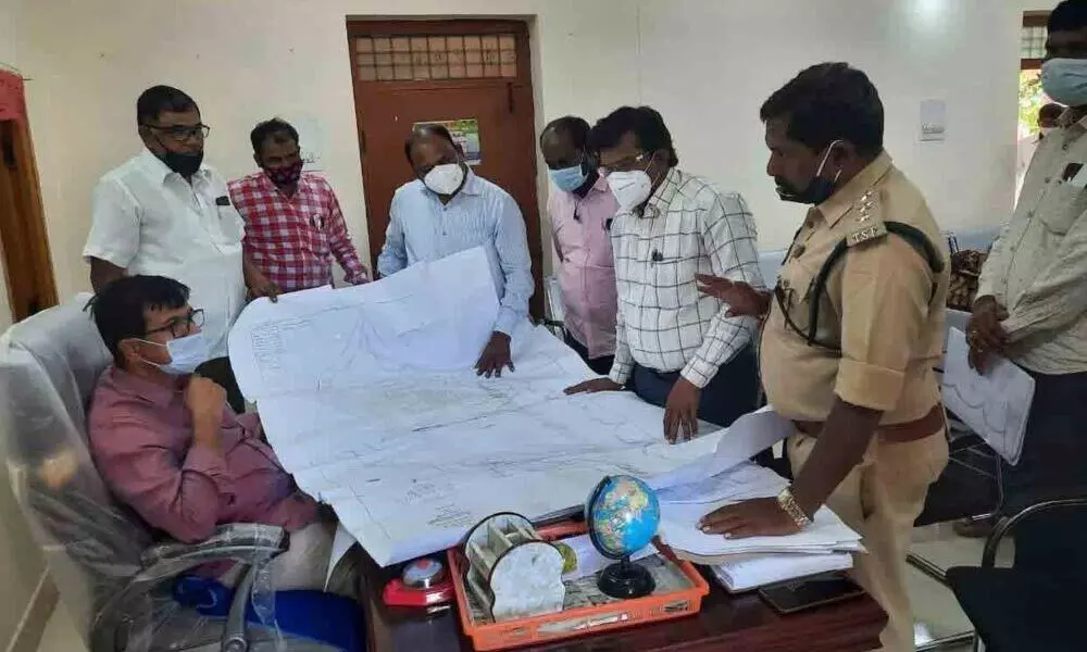 Officials examining the map of forest lands in Chandampeta mandal, at Tahsildar office in Chandampet on Wednesday