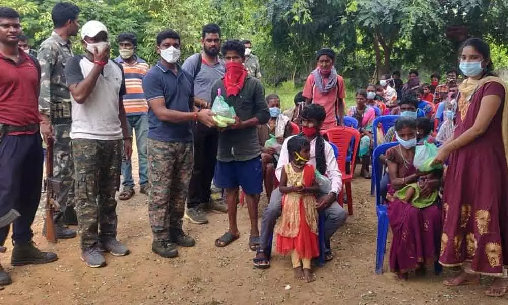 Police personnel distributing medicines and daily essentials to tribal people at a free health camp in Cherla mandal
