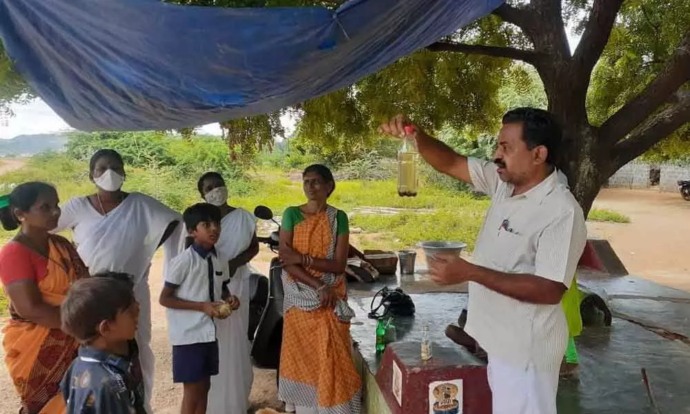 Health department staff educating people on controlling the mosquito larvae in a rural area