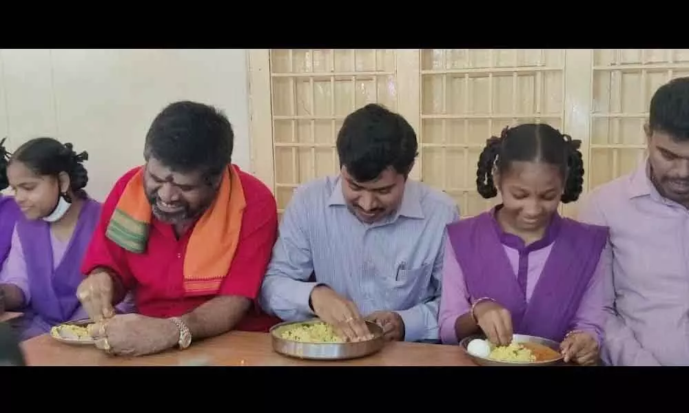 Tourism Minister M Srinivasa Rao and District Collector A Mallikarjuna having meals at Chandrampalem ZP High School along with students in Visakhapatnam on Tuesday