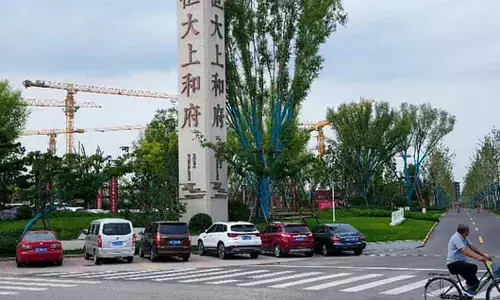 FILE - In this Sept. 15, 2021, file photo, a man bicycles past an Evergrande new housing development in Beijing. (Photo | AP)