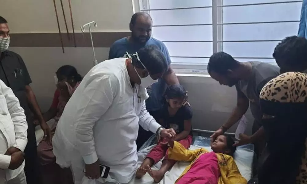 Speaker Pocharam Srinivas Reddy interacting with a student, who fell sick after eating mid-day meals, at the local area hospital in Banswada on Wednesday