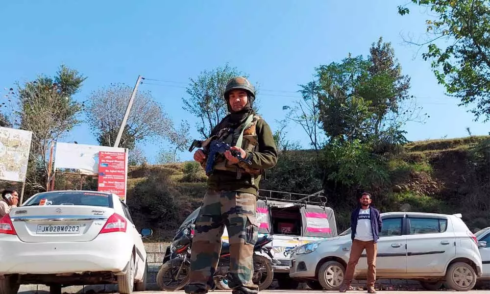 A security personnel stands guard after closing vehicular traffic from Thanamandi to Rajouri