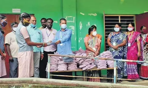 Appavu, a Mathematics teacher, handing over school uniforms to students