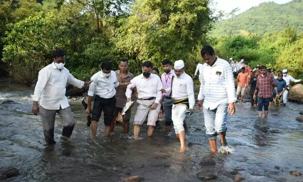 Wading through waters, Secretary of Union Ministry of Tribal Affairs Anil Kumar Jha and other officials visit the tribal hamlet in Visakhapatnam on Tuesday