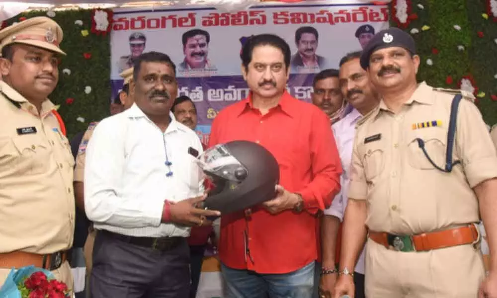 Actor Suman giving away a helmet to a police personnel at Kazipet in Hanumakonda district on Sunday