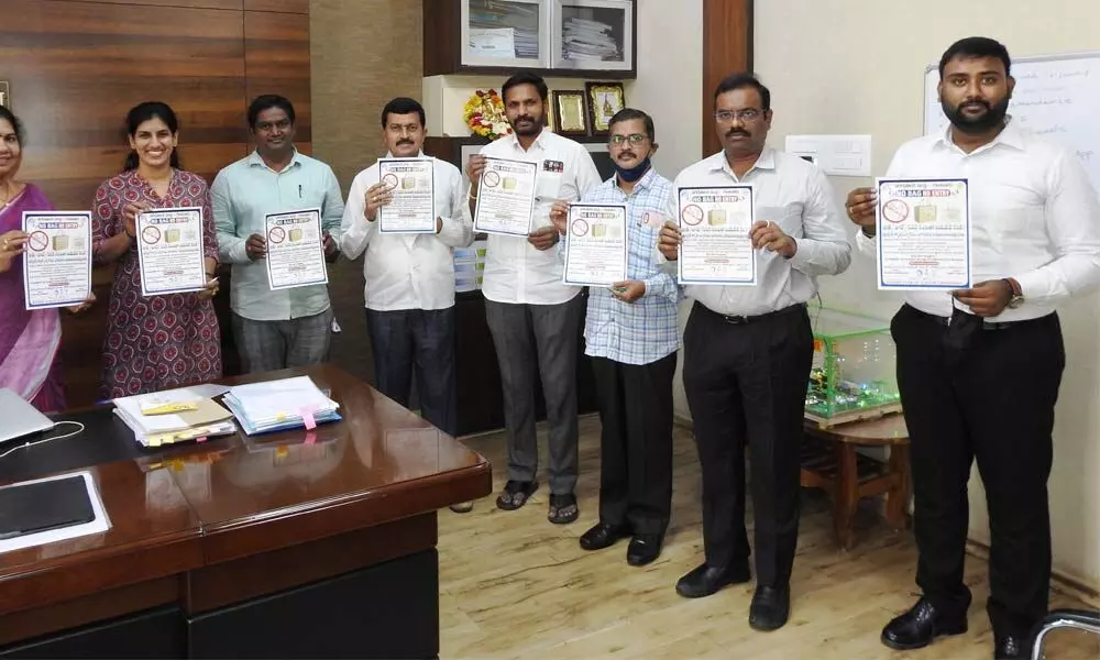 Municipal Commissioner Challa Anuradha and other officials releasing posters on ban on use of plastic carry bags at a programme held at the GMC office in Guntur on Tuesday