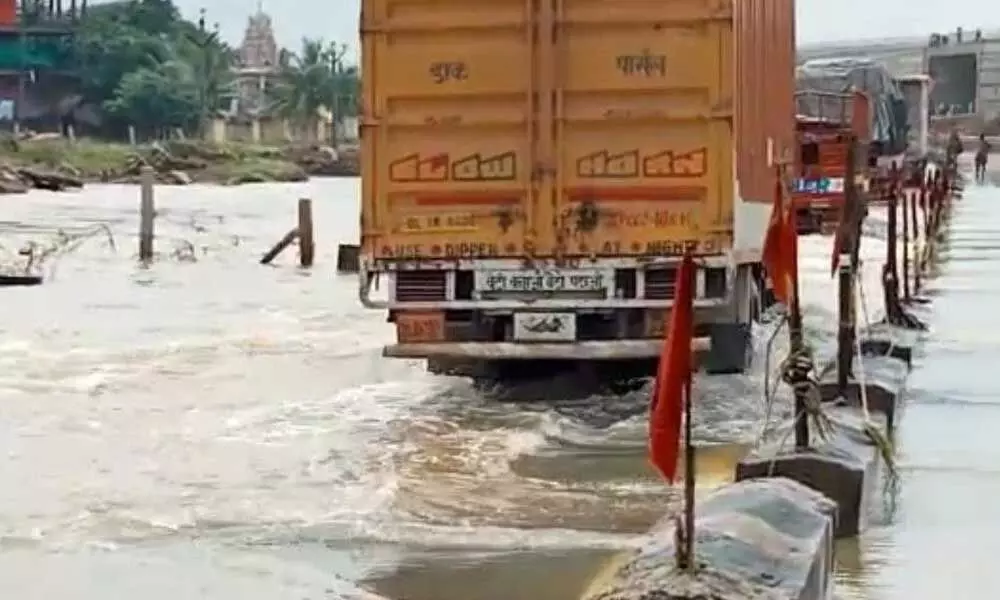 Heavy vehicles wading throughn floodwater on the National Highway at Manubole on Tuesday