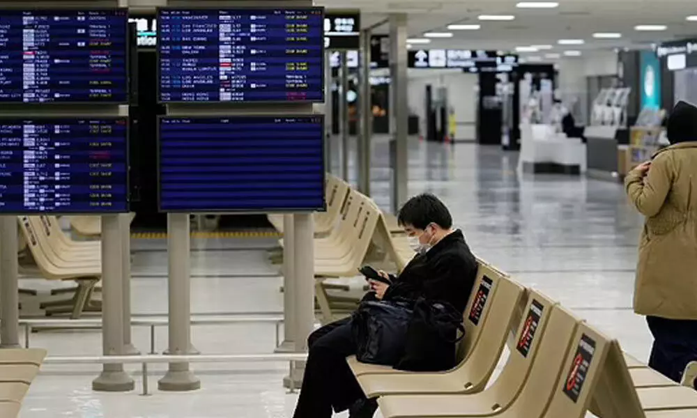 A passenger rests near arrival information screens for international flights at the Narita International Airport in Narita, east of Tokyo.
