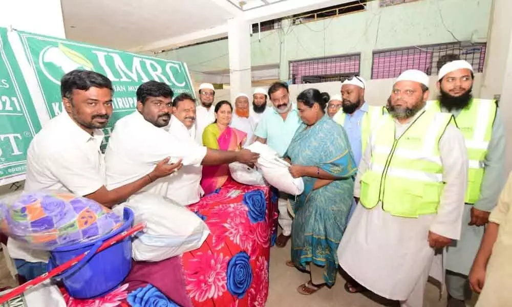 Mayor Dr R Sirisha along with corporation standing committee member SK Babu distributing relief kits to the flood-affected at Srikirshna Nagar in Tirupati on Friday.