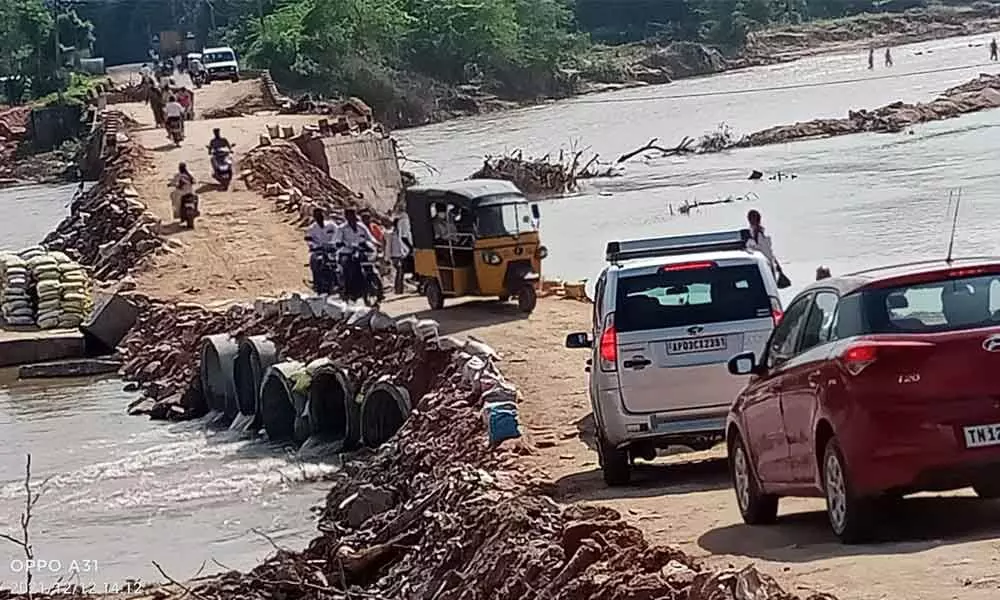 Vehicles including cars going on the temporary road across Swarnamukhi River at Chiguruvada in Tirupati rural mandal