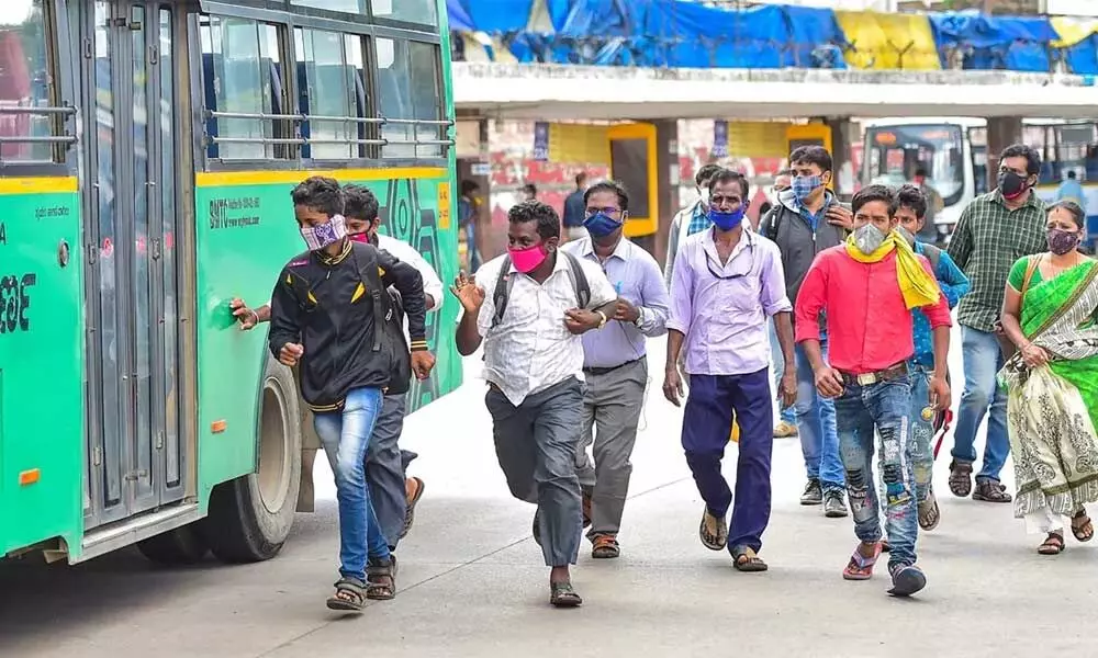 People rush to board a city bus at Majestic bus stand in Bengaluru