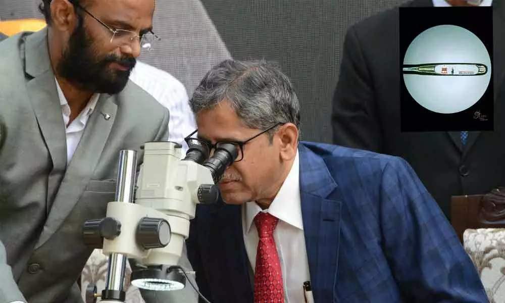 CJI NV Ramana watching Mattewada Ajays handcrafted micro art with a microscope; [Inset Pic: Miniature art of CJI NV Ramana and Supreme Court ]