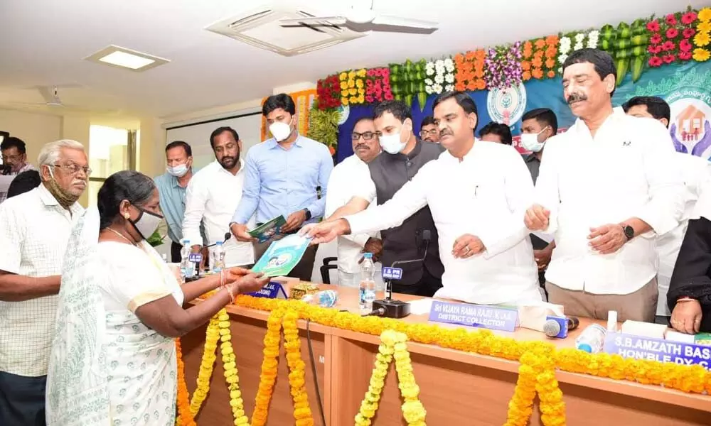 Deputy Chief Minister Amzath Basha handing over the documents to beneficiaries under JSHGP in Kadapa on Tuesday