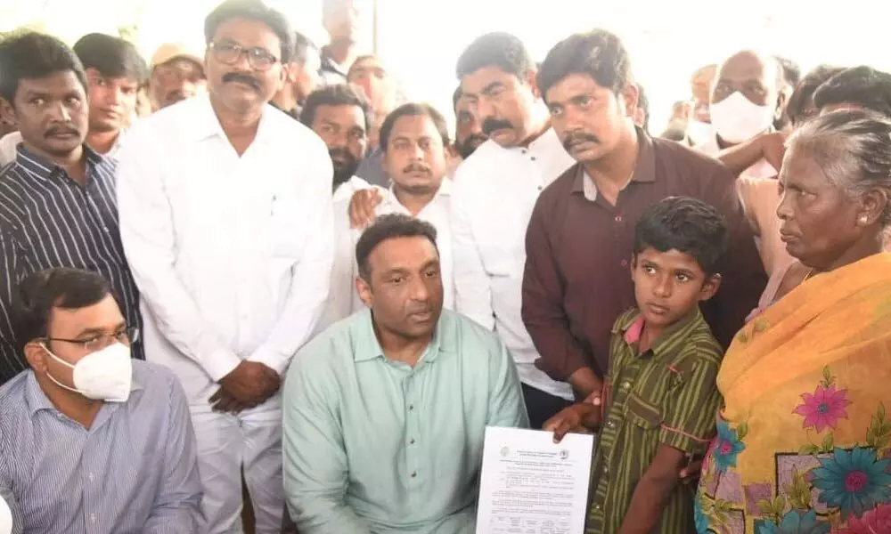 Minister Mekapati Goutham Reddy extending financial assistance to the boy, who lost his parents in a recent mishap, in Atmakur on Wednesday