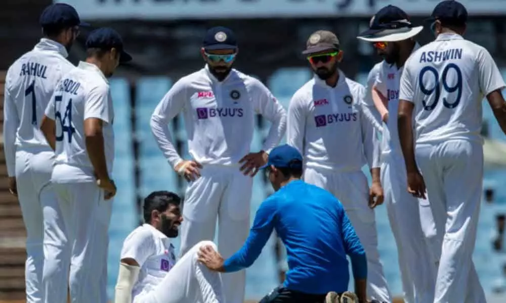 Indias bowler Jasprit Bumrah (bottom left) is attended by team physio Nitin Patel after hurting his ankle. The sprain forced the pace spearhead off the field on the third day of the first Test against South Africa at Centurion Park in Pretoria, here on Tuesday.