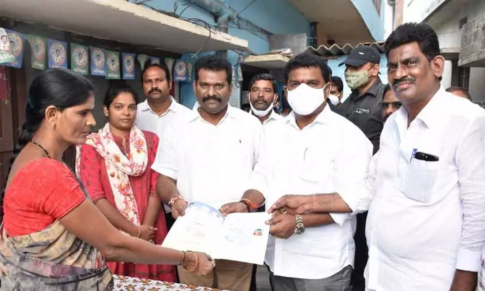 Mayor Kavati Siva Naga Manohar Naidu distributing house site pattas to a beneficiary in Guntur on Wednesday