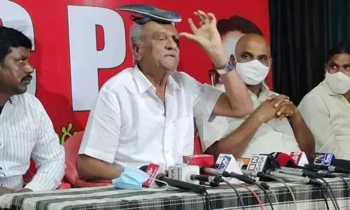 CPI national secretary K Narayana keeps chappal on his head in protest against proposed GST hike on footwear, during a press meet in Tirupati on Friday