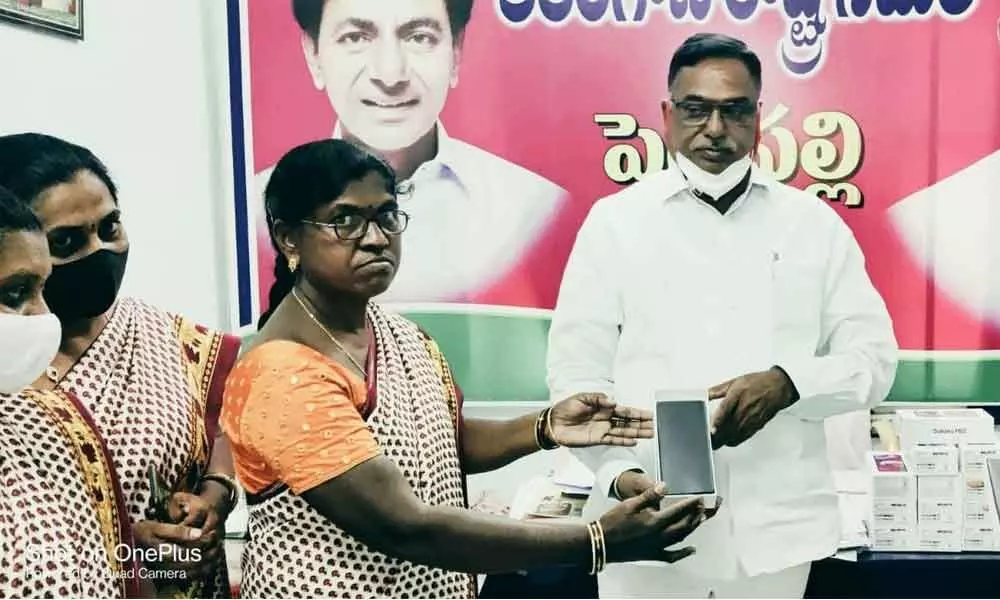MLA Dasari Manohar Reddy and CDPO K Kavita distributing smart phones to Anganwadi teachers in Peddapalli on Monday
