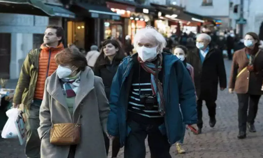 Pedestrians, some wearing protective face masks to prevent the spread of the COVID-19, walk in street market, in Paris.