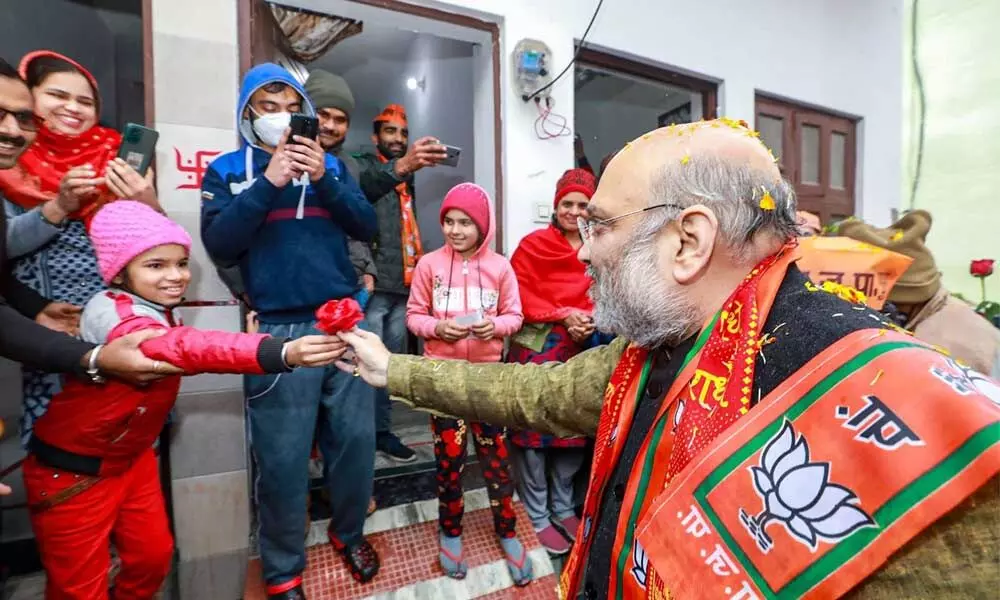 Union Home Minister Amit Shah receives a flower from a child during his door-to-door campaign ahead of Uttar Pradesh Assembly elections, in Kairana